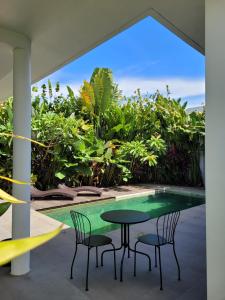 a patio with a table and chairs next to a pool at Tranquil 2BR Pool Villa - Fast WiFi - Work-Friendly - Near Echo Beach in Tumbak Bayuh