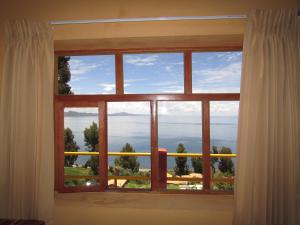 ein Fenster mit Meerblick in der Unterkunft Titicaca Chaska Wasi Amantani in Ocosuyo
