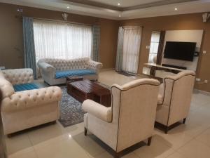 a living room with couches and a flat screen tv at Tina's Place in Lilongwe