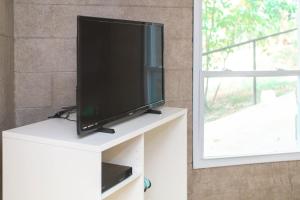 a flat screen tv sitting on a white cabinet next to a window at Small piece of heaven on the lake - King suite in Richfield