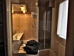 a bathroom with a sink and a shower with towels at Hotel Restaurant de la Marne in Paimpol