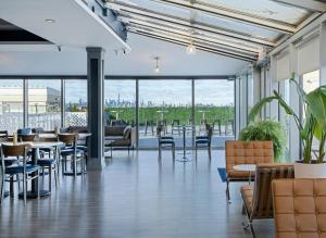 a restaurant with tables and chairs and windows at voco Fiorello - LaGuardia East by IHG in Queens