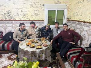 a group of men sitting around a table with food at KETAMA home stay in Tlata Ketama