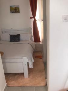 a bedroom with a white bed and a window at Sunstone Studio- Ngong Rd Near Junction Mall in Nairobi +6 photos