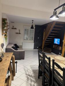 a living room with a couch and a staircase at Les Rolliannes Maison au village in Surques