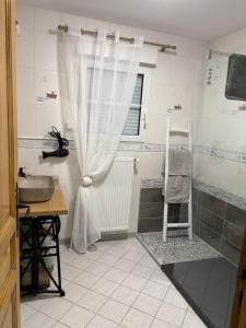 a bathroom with a sink and a shower curtain at Les Rolliannes Maison au village in Surques