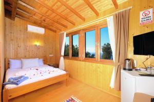 a bedroom with a bed and a tv and windows at BlueSea Faralya-Sardalya Full Deniz Manzaralı in Kızılcakaya