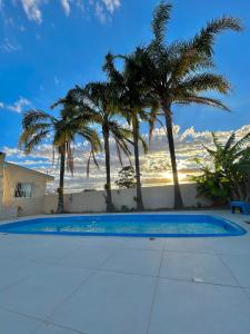 a swimming pool with palm trees in the background at Loft incrível e completo in São Lourenço do Sul