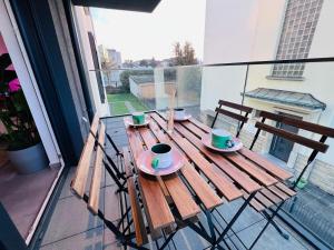 a wooden table with cups and saucers on a balcony at Lovely 1 bedroom apartment w balcony&parking-BON10 in Luxembourg