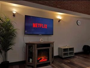 a television on a wall with a fire in a fireplace at Chic Central, Relaxing, Restful, Retreat, Heated Floors, High Ceiling, Open Plan, City Centre, 1BR in Sheffield