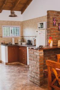 eine Küche mit einem weißen Kühlschrank und einer Ziegelwand in der Unterkunft Cabaña Morada del Cerro - Cabaña Chañar - in Capilla del Monte