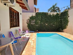 a swimming pool with chairs and a table next to a building at Casa 3 Quartos 5 min Centro 15 min aeroporto in Foz do Iguaçu