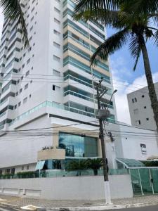 a tall building with a palm tree in front of it at Apartamento praia grande frente do mar in Praia Grande