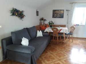 ein Wohnzimmer mit einem blauen Sofa und einem Tisch in der Unterkunft Gästehaus Reisacher - Mehrbettzimmer in Peiting + 22 Fotos