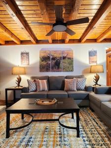 Stylish Forest Lodge with Large Hot Tub, Firepit and Fireplace minutes to Gore Mountain في North Creek: غرفة معيشة مع أريكة ومروحة سقف +60 صورة