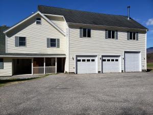 a large white house with four garage doors at River Retreat with Hot Tub in Bethel