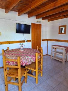 ein Esszimmer mit einem Tisch und einem TV an der Wand in der Unterkunft Nahucar in El Bolsón