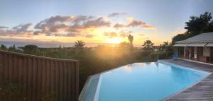 una piscina con puesta de sol en el fondo en Villa Libellule, en Grand-Bourg