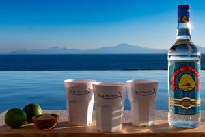 a bottle of wine and three cups on a table with a bottle of alcohol at Villa Belle Galante in Grand-Bourg