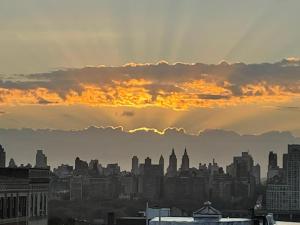 a city skyline with the sun shining through a cloudy at See NY Now Sleeps 21 in Union City