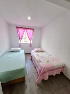 a bedroom with two beds and a window with pink curtains at Casa Fracc Paseos de la Plata Pachuca Hidalgo in Pachuca de Soto