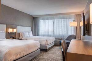 a hotel room with two beds and a chair at Orange County Hotel in Santa Ana