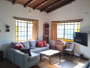 Una sala de estar con un sofá y un televisor. en Casa Buena Vista, en Unquillo