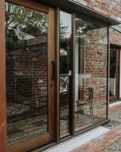 a glass door with a chair in front of a brick building at Braithwaite Hobart - Chic Retreat with Outdoor Bath in Hobart +20 photos