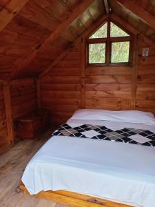 a bed in a wooden room with a window at Eco Cabaña en el Campo in La Vega