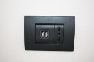 a black light switch on a white wall at The One Malpensa Rooms in Vizzola Ticino +21 photos