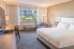 a hotel room with a bed and a desk and a window at voco Orange County - Airport by IHG in Santa Ana +66 photos