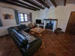 een woonkamer met een leren bank en een open haard bij Hacienda Riogordo in Ríogordo