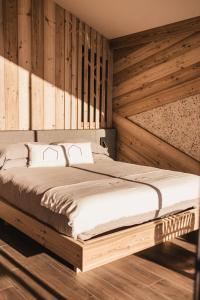 a bed in a room with a wooden wall at Borgo Antico in Sappada