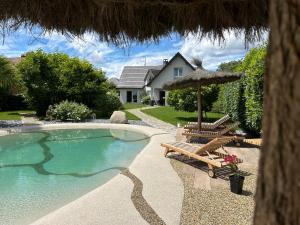 a swimming pool with two chairs and an umbrella at Grande maison au calme in Ensisheim