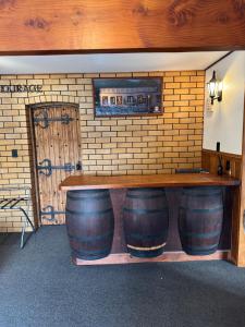 a bar with three wine barrels and a brick wall at Surf, Play and Stay in Tairua