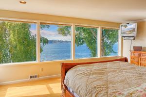 una camera da letto con grandi finestre e un letto in esso di Four Stone Beach House a Vashon