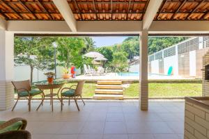 安格拉杜斯雷斯Casa em Angra com Piscina e Descida para Jet Ski的带桌椅和游泳池的露台