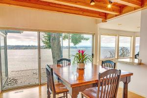 una sala da pranzo con tavolo, sedie e una grande finestra di Four Stone Beach House a Vashon