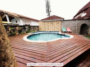 a wooden deck with a swimming pool on a house at Castelinho Solemar - Apart Premium a Passos da Praia in Praia Grande