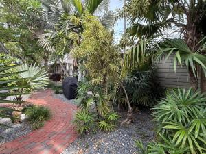 a garden with a brick walkway next to a building at Osprey Suite - Southernmost Sanctuary in Key West +9 photos