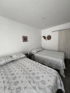 two beds in a room with white walls at Ancestral Casa de Campo in Roldanillo