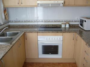 a kitchen with a white stove and a sink at Seaside cottage in Pobla de Montornés