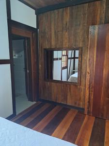 a mirror in a room with wooden walls at Caminhos da Serra do Tabuleiro - Casa Centenária Enxaimel 1915 in São Bonifácio +71 photos