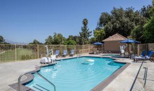 a large swimming pool with chairs and umbrellas at Ayres Suites Diamond Bar in Diamond Bar