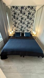 una camera da letto con un letto blu con una carta da parati in bianco e nero di Le Pic D'Etretat a Étretat