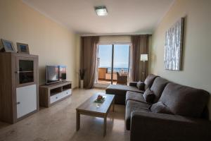 a living room with a couch and a television at Residencial Playa de La Arena in Puerto de Santiago