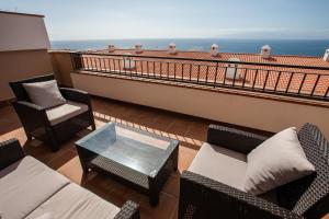 a balcony with chairs and tables and the ocean at Residencial Playa de La Arena in Puerto de Santiago
