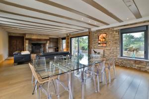 a dining room with a glass table and chairs at Luxueuse Longère 350m2 "Le Grand Kerfra" au Vignoble Domaine Lamballe, Baden, Golfe du Morbihan in Baden