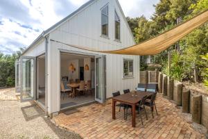 a house with a patio with a table and chairs at Boathouse Onetangi - Stay Waiheke in Waiheke Island +19 photos