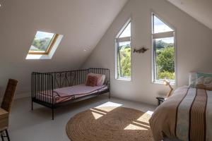 a bedroom with a crib and two windows at Boathouse Onetangi - Stay Waiheke in Waiheke Island